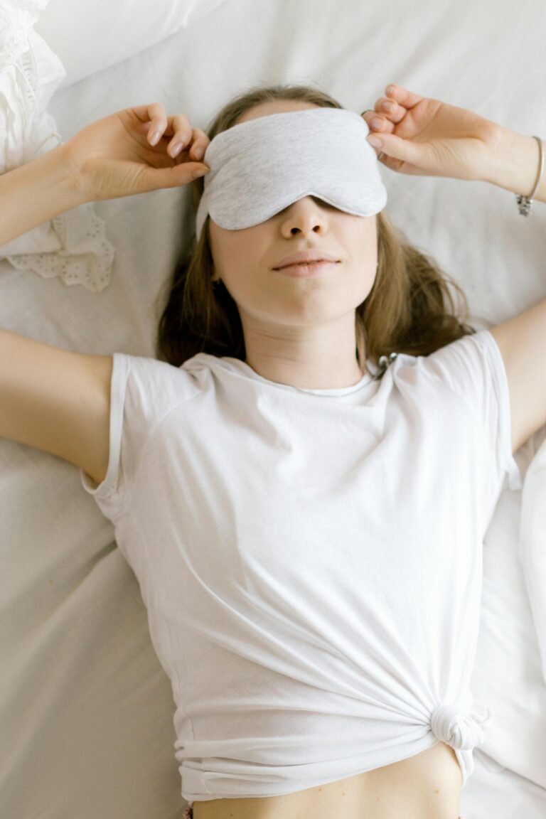 Vrouw met slaapmasker die ontspannen ligt, klaar voor een rustgevende nacht met slaapthee